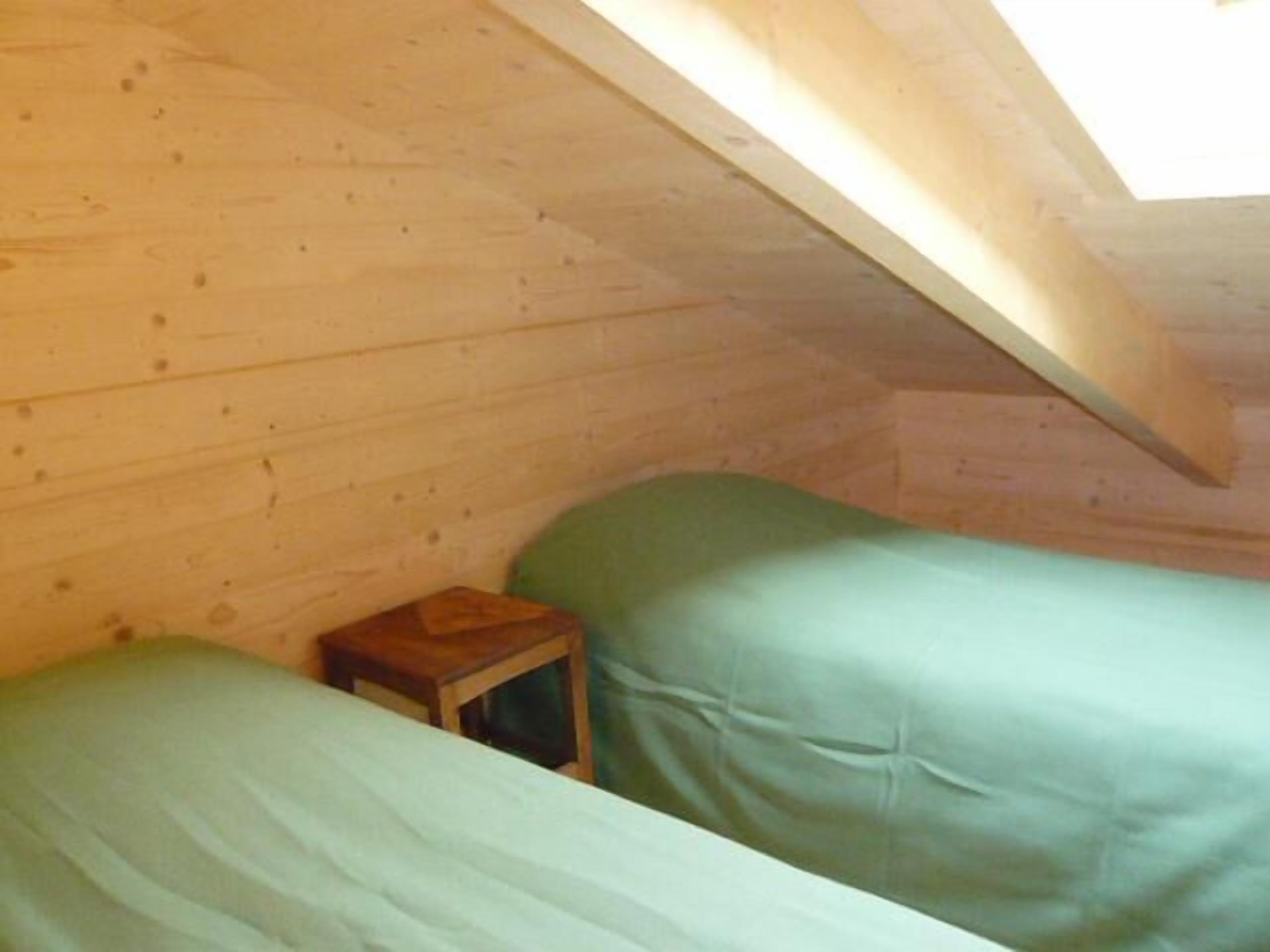A small, cozy room with two beds and a small wooden table.