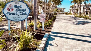 Shell Island Beach Club skilt med udsigt over stranden, palmer og en anlagt sti.