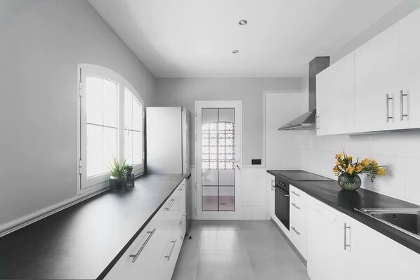 Une cuisine moderne avec des meubles blancs, un plan de travail noir et une fenêtre offrant une belle vue.