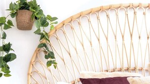 A bed with a woven headboard, a hanging plant, and a striped blanket. - Mid-Century Modern Retro Beach House (Caloundra Region)
