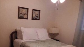 A neatly made bed with white linens, a bedside lamp, and two framed pictures on the wall. - Relax in the country at Countryside Villas! - Villa A (Jackson)