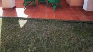 An outdoor patio with a table and chairs, a grill, and a door with curtains. - Sardinia Villasimius coastline, ins (Quartu Sant'Elena)
