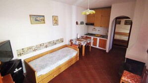 A small, compact room with a single bed, a kitchenette, and a dining area. - Sardinia Villasimius coastline, ins (Quartu Sant'Elena)