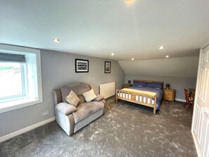 Ein Schlafzimmer mit einem Bett, einem Sofa, einem Fenster und einer Heizung.