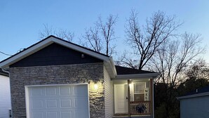 Una casa de dos pisos con fachada de piedra, un garaje y un porche delantero.