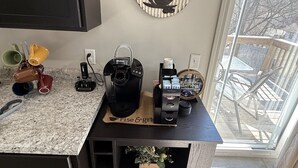 Una cocina con cafetera, decoración de pared con motivos de café y vistas al exterior.