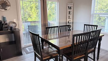 A dining area with a wooden table and chairs, a coffee machine, and a 'WELCOME' sign.