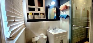 A bathroom with a toilet, sink, mirror, and shelves with baskets.