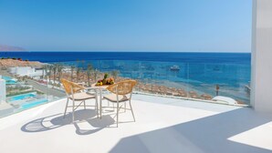 A balcony with two wicker chairs and a small table, overlooking a clear blue sea and a resort area. - Meraki Sharm El Sheikh Resort (Sharm El Sheikh)