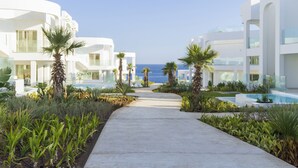 A pathway leading to a modern building with a pool, surrounded by palm trees and greenery. - Meraki Sharm El Sheikh Resort (Sharm El Sheikh)