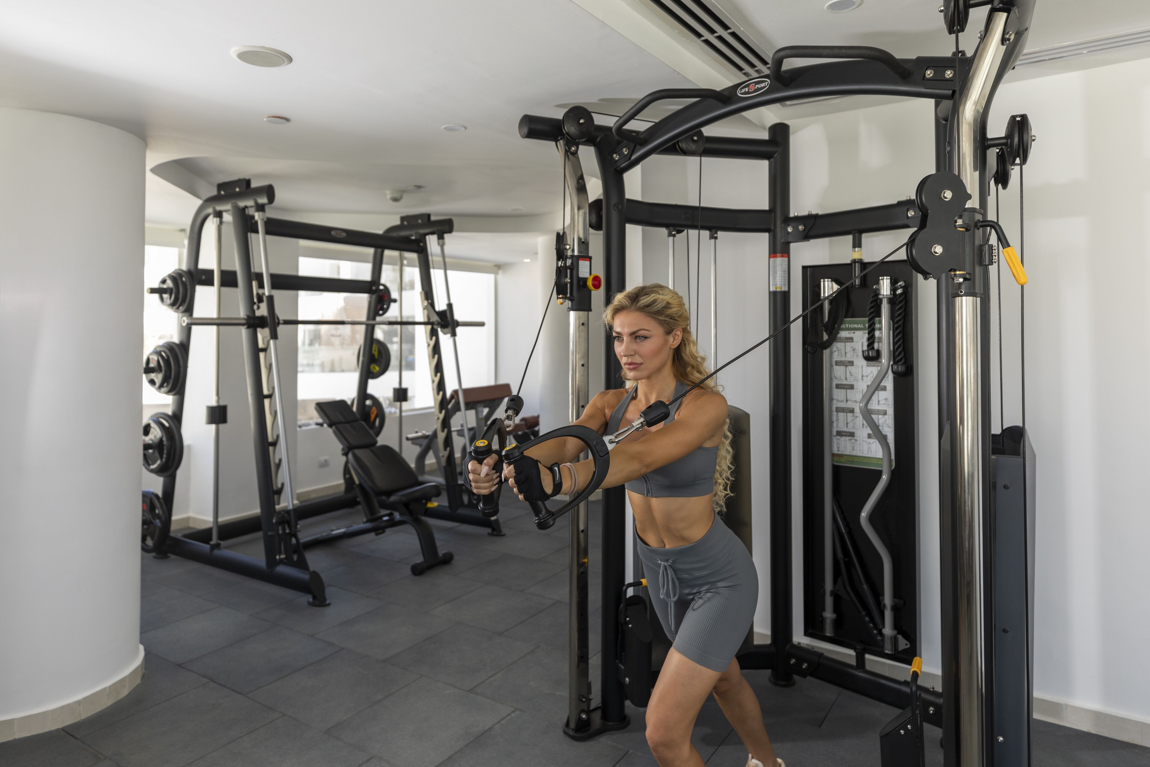 A gym with exercise equipment, including a cable machine and weight benches.