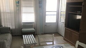 Ein Essbereich mit Tisch für zwei Personen, Deckenventilator und Blick nach draußen durch eine Tür.