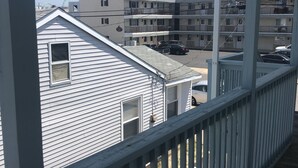 Ein Balkon mit Blick auf ein mehrstöckiges Gebäude, das mehrere Balkone und parkende Autos zeigt.
