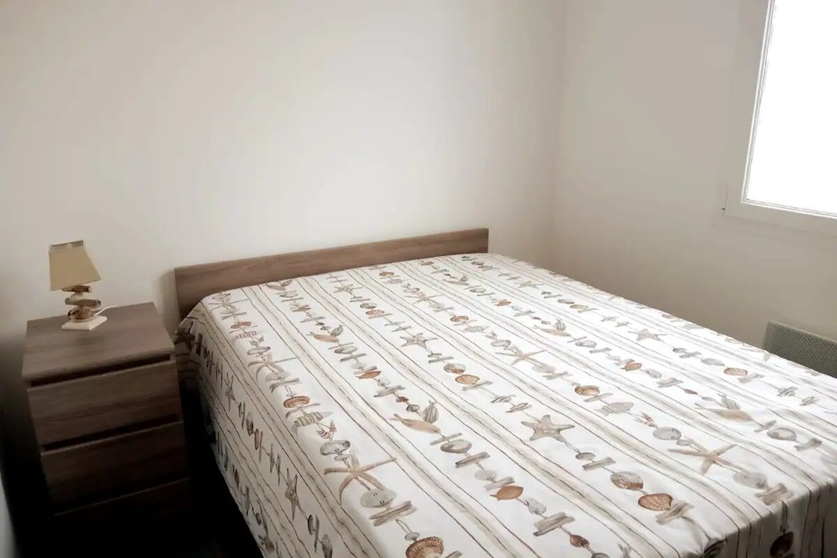 A bedroom with a bed, a nightstand, and a window.