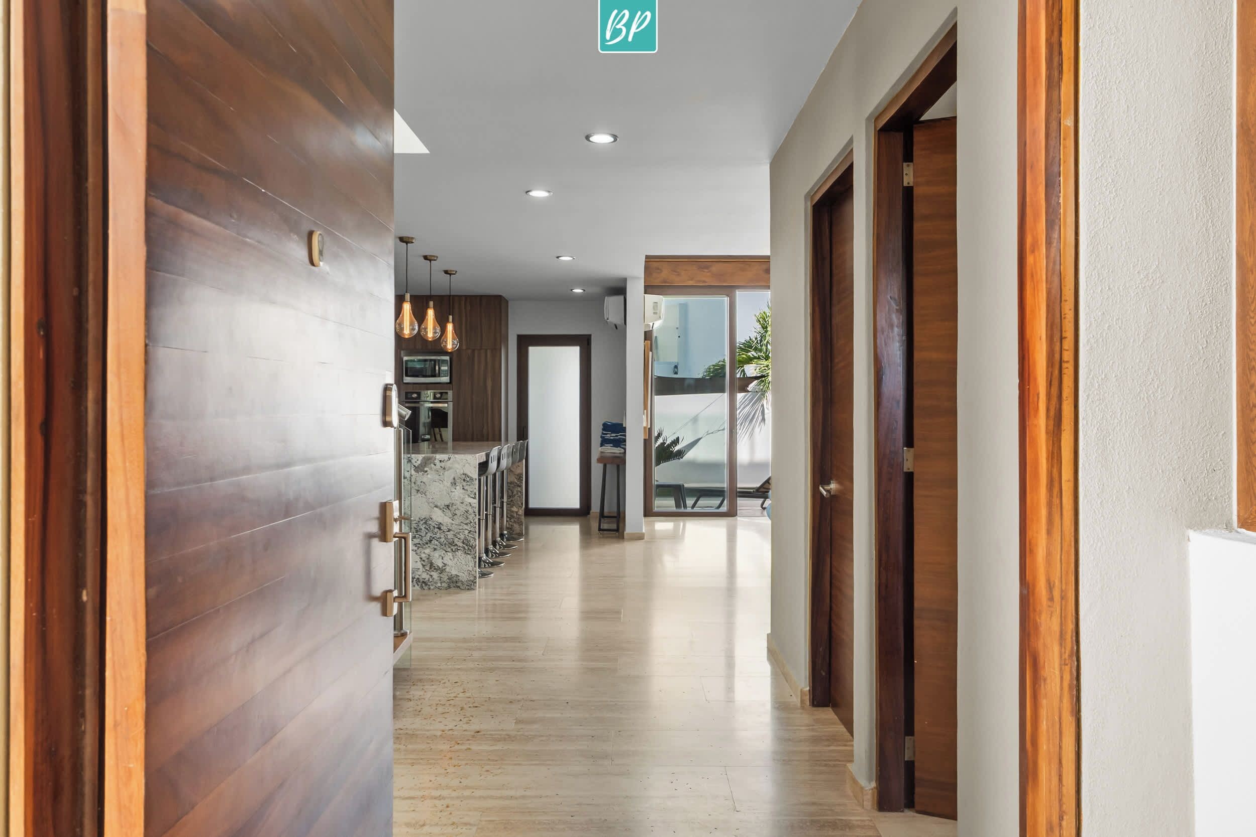 A hotel corridor with wooden flooring, a marble bar area, and a view through a glass door.