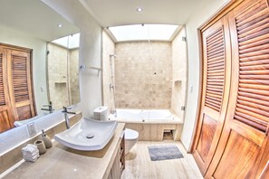 Un baño moderno con un espejo grande, un lavamanos, una bañera y puertas de madera.