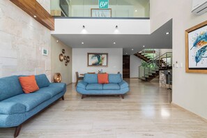 A modern interior with two sofas, a staircase, and a view of the outdoors.