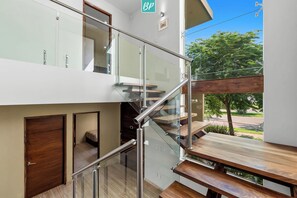 A modern interior with a glass staircase, wooden flooring, and a view of greenery outside.