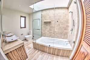 A modern bathroom with a glass-enclosed shower, a large bathtub, and a vanity with three sinks.