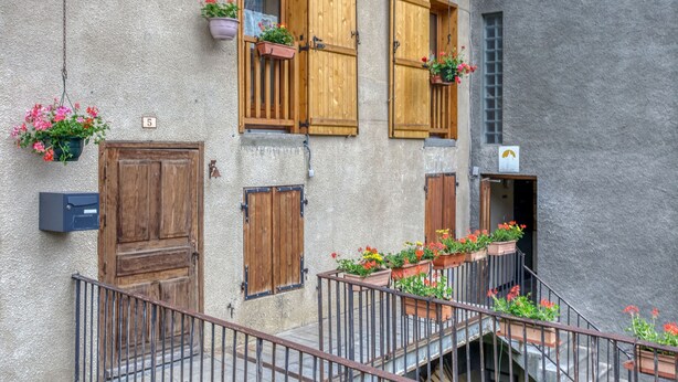 Un bâtiment avec des volets en bois, une boîte aux lettres et des jardinières sur les rebords des fenêtres.