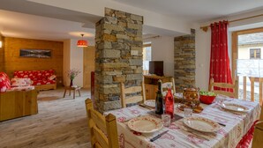 Un coin repas agrémenté d’un pilier en pierre, de meubles en bois et d’une table dressée pour deux personnes.