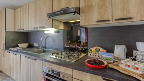 Une cuisine moderne avec des meubles en bois, un évier en acier inoxydable et une cuisinière à gaz.