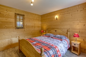 A wooden-paneled bedroom with a bed, nightstands, and a window.