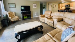 Un salon comprenant un canapé, un fauteuil, une table basse, un téléviseur et un ventilateur de plafond.