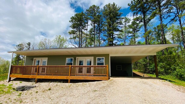Une maison de plain-pied avec une terrasse en bois et un porche couvert.