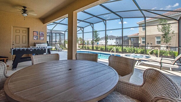 An outdoor patio with a pool, a foosball table, and wicker furniture.