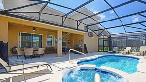A pool area with lounge chairs, a hot tub, and a covered patio with outdoor furniture.