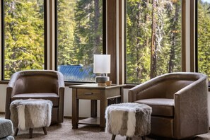 Enjoy a serene forest view from the comfort of this stylish room, featuring two plush armchairs and a desk.