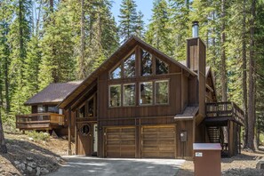 Overlooking the forest, this lodge features a spacious main building with a balcony, large windows, and a chimney.