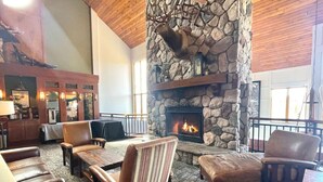Ein gemütlicher Loungebereich mit Ledersofas und -sesseln, einem Steinkamin und Blick ins Freie.