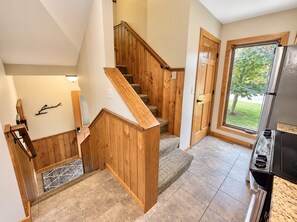 Une cuisine équipée d’une cuisinière intégrée, d’un escalier en bois et d’une grande fenêtre.