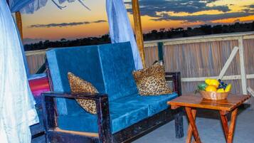 Relax in the outdoor seating area with a sofa and armchairs, surrounded by a wooden fence and a beautiful view.