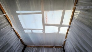 Une pièce dotée d’une grande fenêtre divisée en plusieurs panneaux, de poutres en bois et d’un mur en métal ondulé.