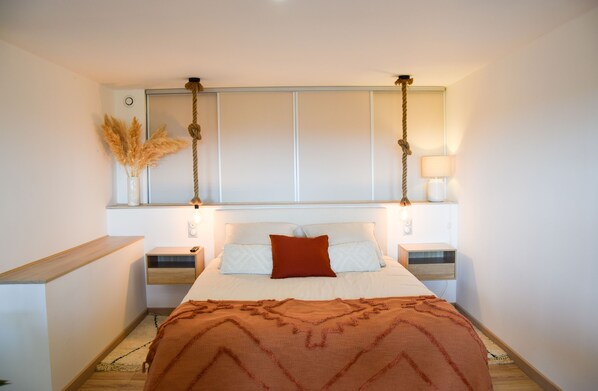 Relax in a serene space with a large bed, bedside tables, and a decorative rope above.