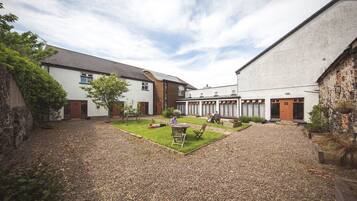 A courtyard with a gravel path, a small lawn, and a seating area with a table and chairs.