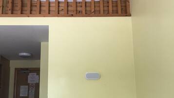 A room with a bunk bed, a single bed, a door with a sign, and a light switch.