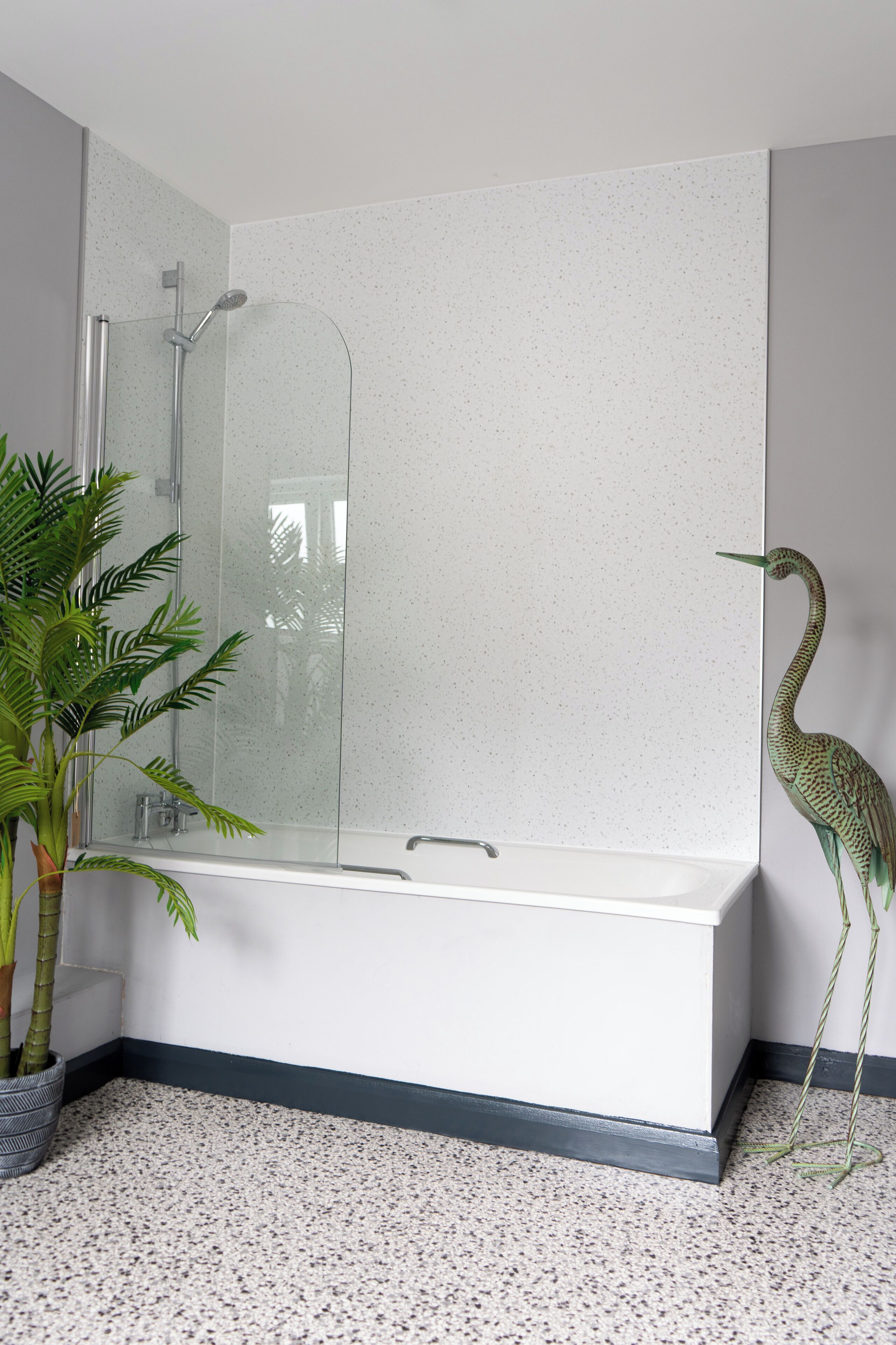 A modern bathroom with a freestanding bathtub, a glass shower enclosure, and a potted plant.