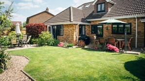 Ein zweistöckiges Haus mit gepflegtem Rasen, Gartenmöbeln und einer Grillanlage.