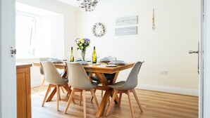 Ein Essbereich mit Holztisch, vier Stühlen und einer Blumenvase.