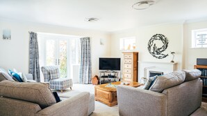 Ein Wohnzimmer mit einer Sofagarnitur, einem Couchtisch, einem Fernseher und einem Kamin.