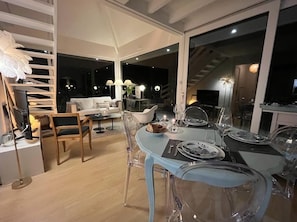 Un espace de salle à manger moderne avec une table en verre prévue pour quatre personnes, entourée de chaises transparentes.