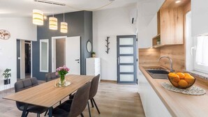 A modern kitchen with a wooden countertop, a sink, and a dining area with a table and chairs.