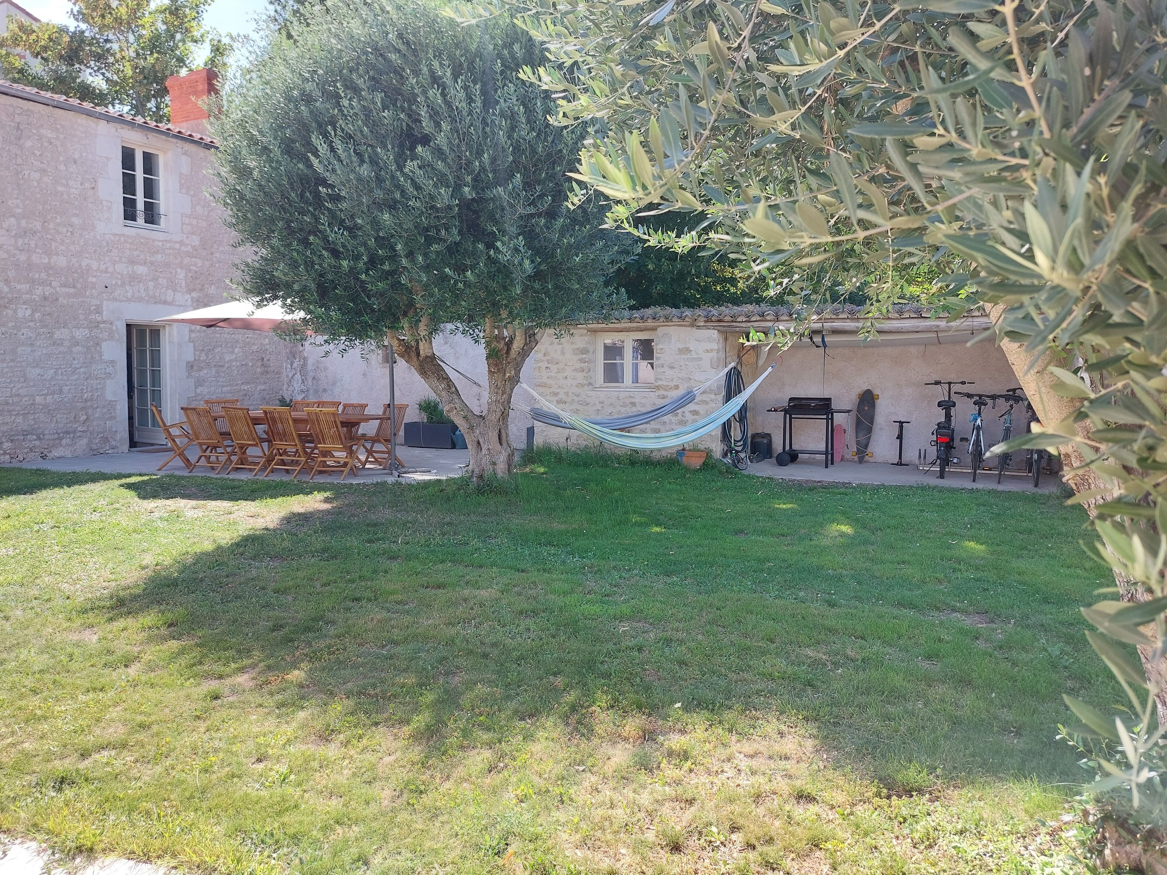 Un bâtiment en pierre doté d’une terrasse, de sièges extérieurs, d’un hamac et de vélos.