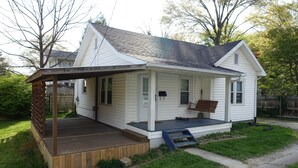 A single-story house with a front porch, a small deck, and a front yard. - The College Cottage - Entire Home (Morehead)