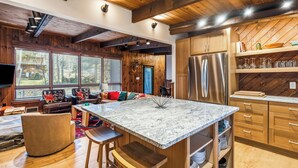 A spacious kitchen with a large island, wooden cabinetry, and a built-in refrigerator.