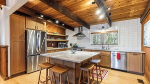 A modern kitchen with wooden cabinets, stainless steel appliances, and a central island with stools.